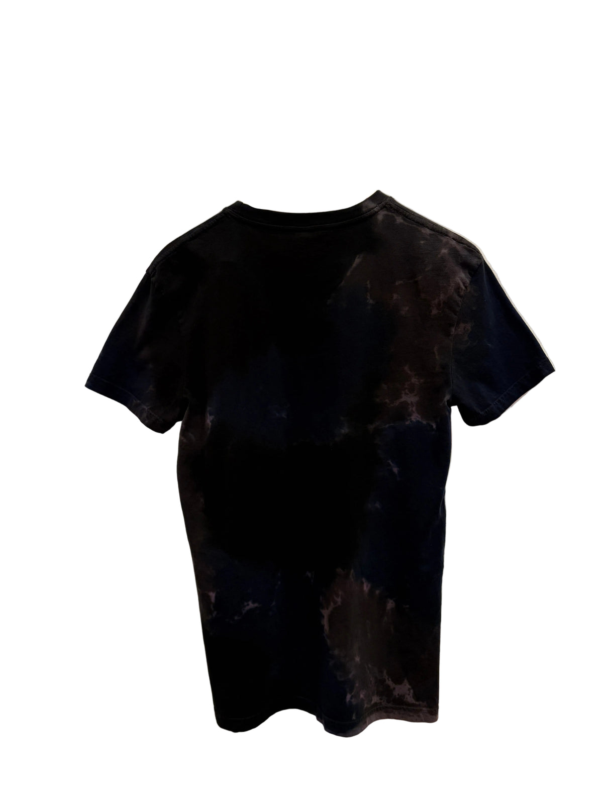 A short-sleeve t-shirt with a black and dark gray handpainted pattern, hanging on a white hanger against a white wall.