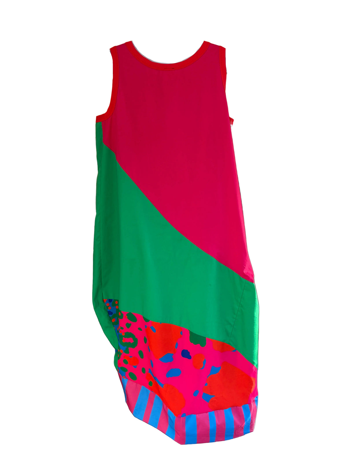 A sleeveless color-block dress with a bright pink, green, and multicolor abstract pattern, displayed on a mannequin in a boutique window.