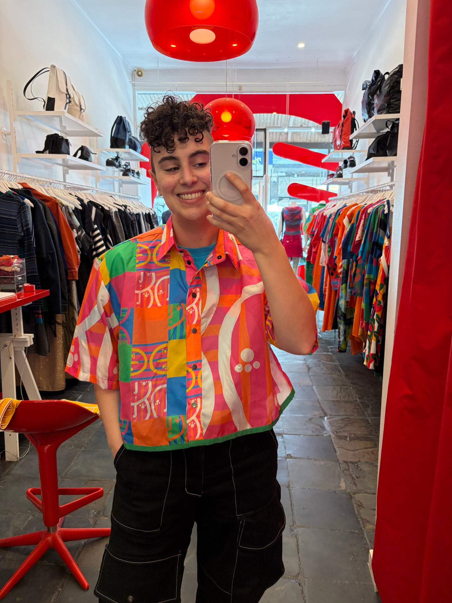 Person taking a selfie in a colorful shirt with a vibrant indoor setting.