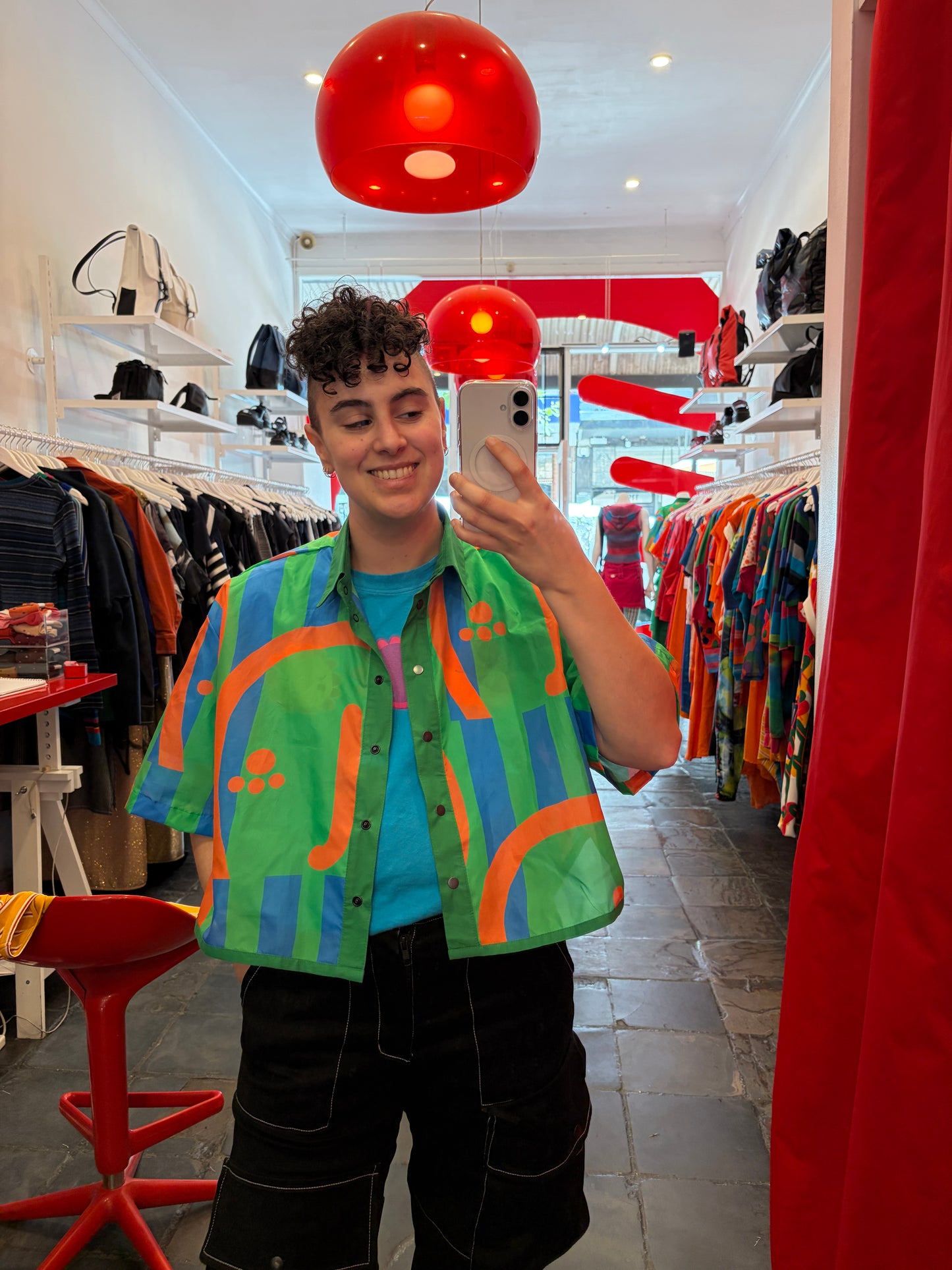 Person wearing a colorful jacket in a store with red chairs and white walls.
